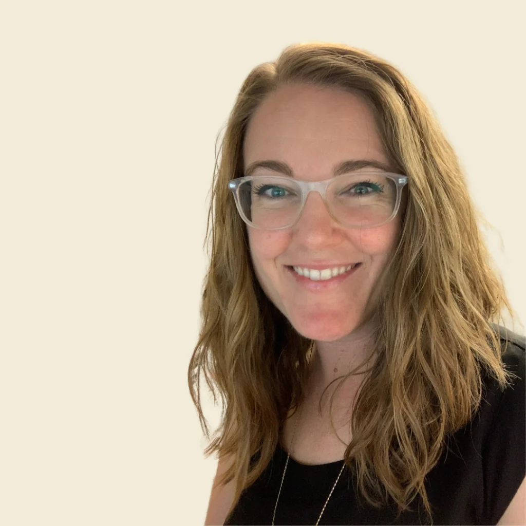 blonde woman with glasses smiling with white backdrop
