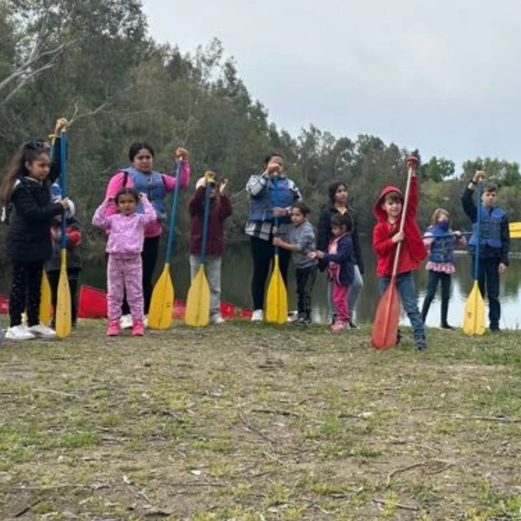 group of kids on a beach holding paddles