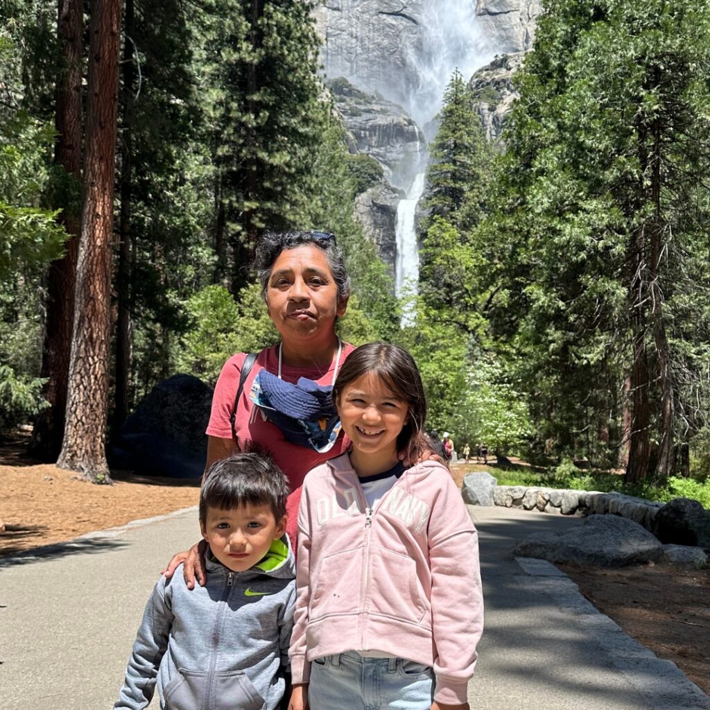 group of kids standing on road in front of trees and waterfall