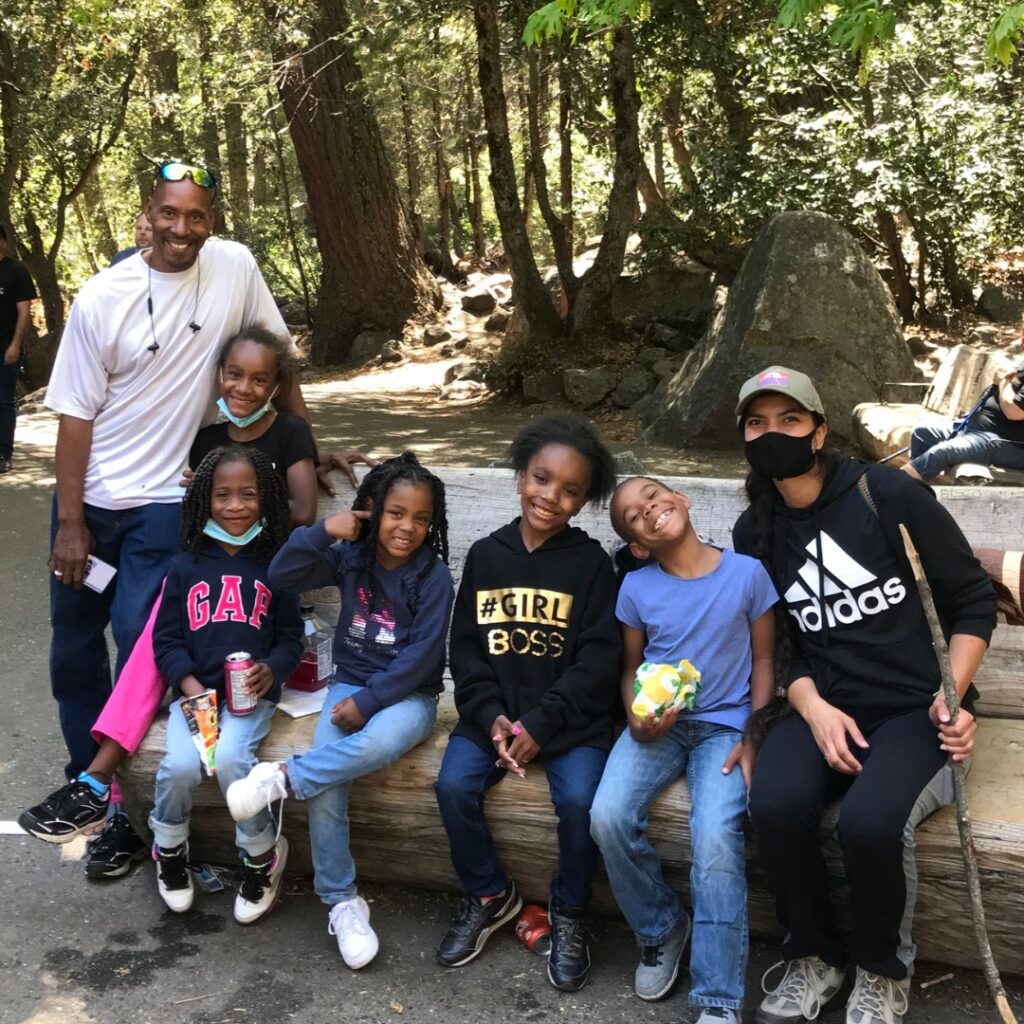 group of people sitting on a log with trees in background