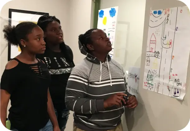 three girls presenting a drawing on a paper
