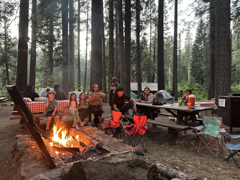 group of people sitting at tables around evening time as the fireplace is going strong