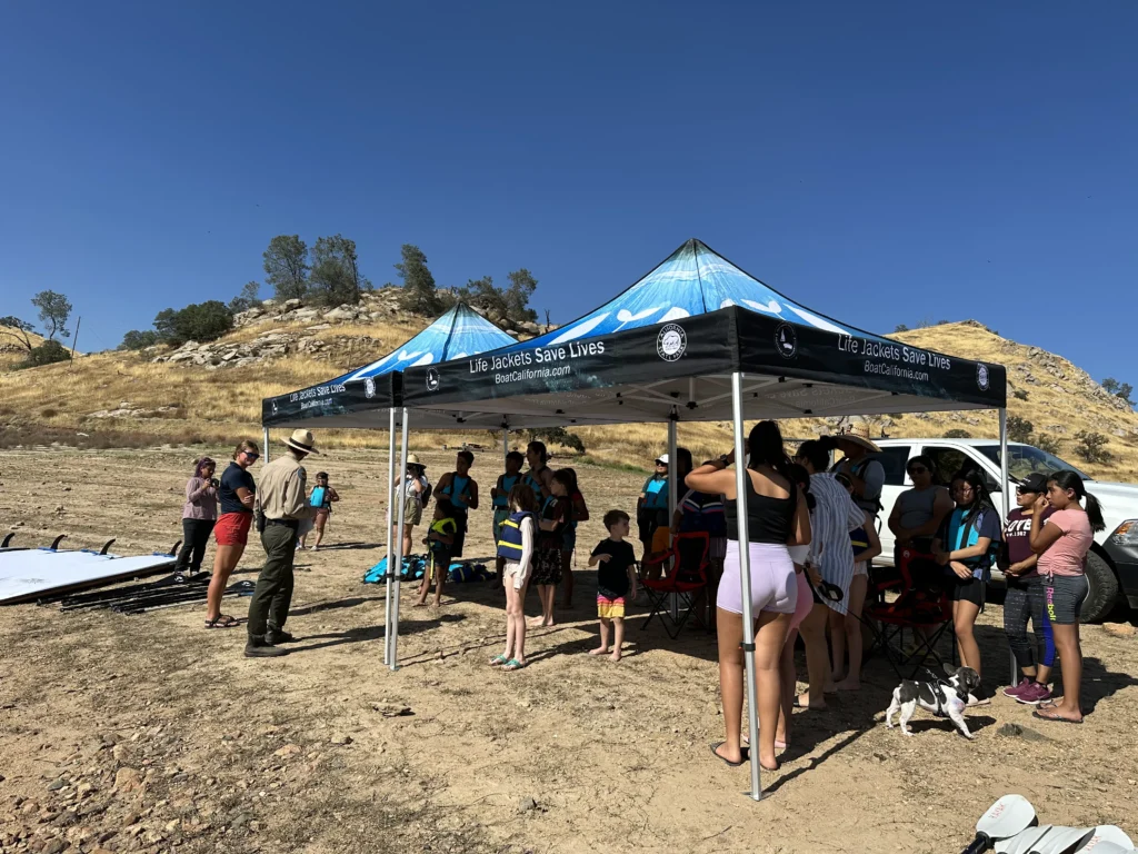 group of people under pop up shades on sandy beach area