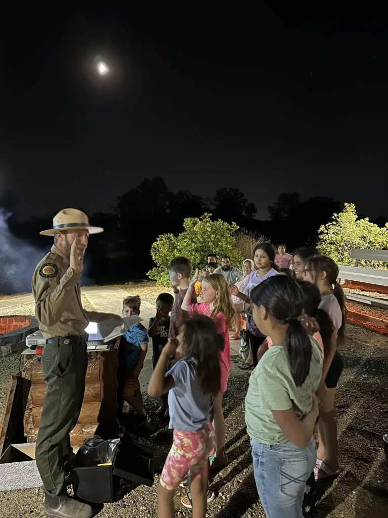 ranger holding up hand taking an oath showing group of kids paying attention