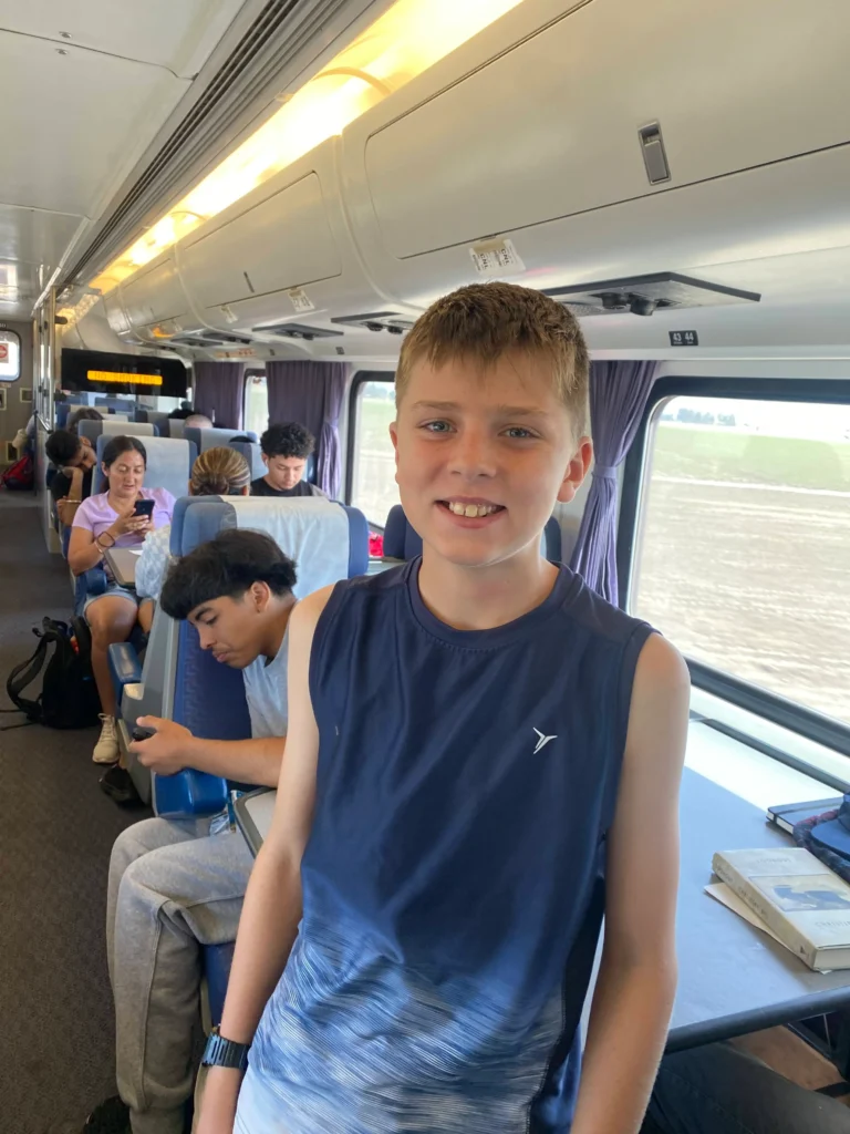 boy smiling at camera and other passengers aboard train in background