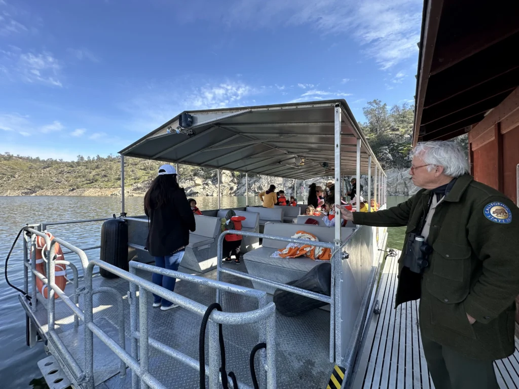 view from dock of covered pontoon boat with a few people on board