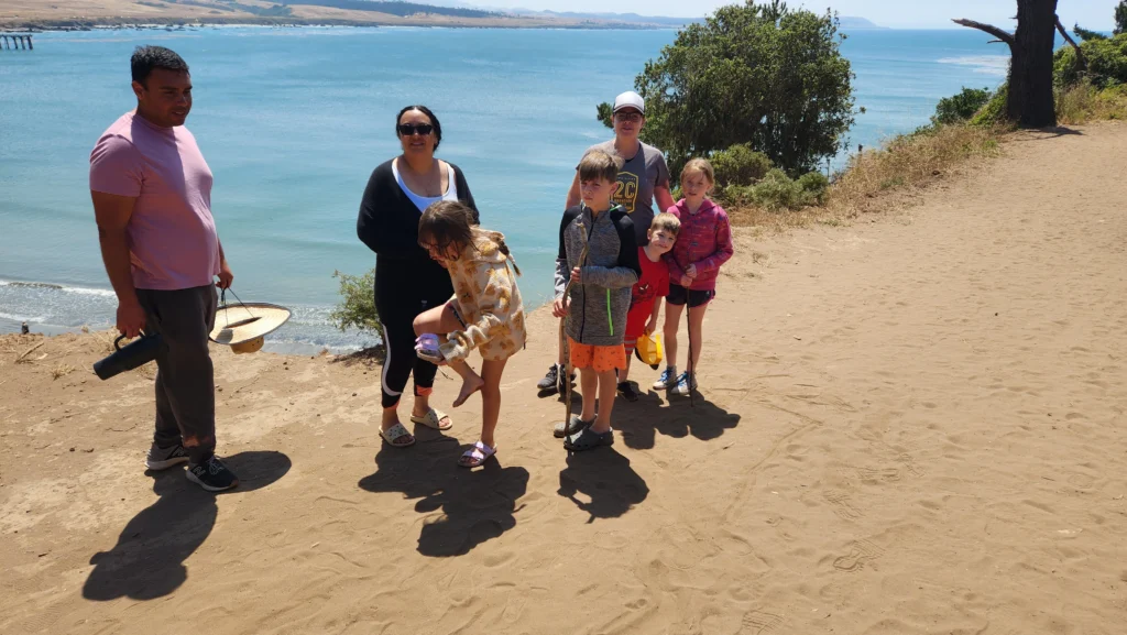 people standing on sandy path overlooking the ocean