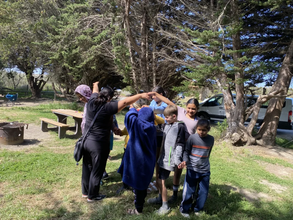 people standing in circle at picnic site surrounded by trees
