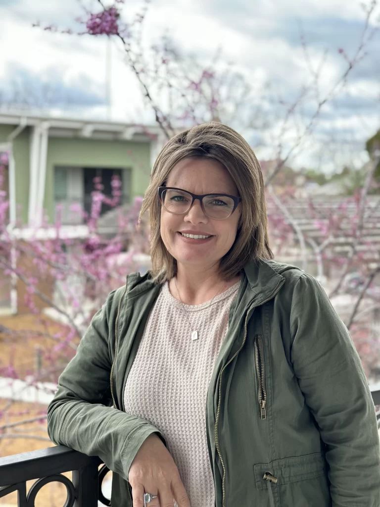 woman in jacket smiling in front of blossoming tree