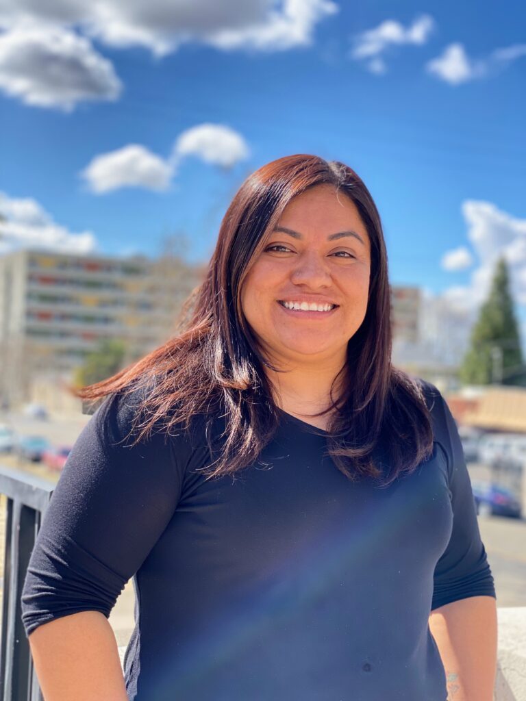 Woman smiling with blue sky and scattered clouds in background